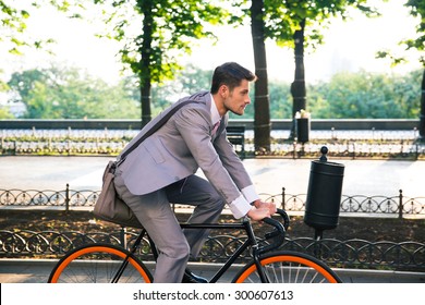 Businessman riding bicycle to work in city park - Powered by Shutterstock