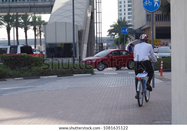 Businessman riding a bicycle to work. Going to\
cross a busy street\
downtown.