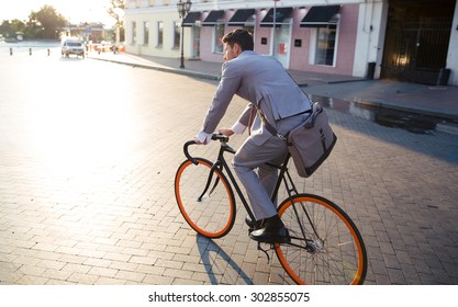 Businessman riding bicycle to work on urban street in morning