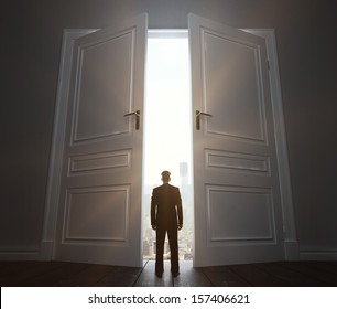 businessman in room with big door to city