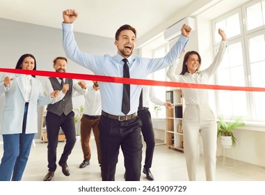 Businessman running and crosses the red finish line in the office, with colleagues supporting and celebrating victory, achievement and success, with the businessman emerging as the winner. - Powered by Shutterstock