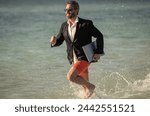 businessman running at summer vacation. business success of businessman. Businessman in suit with laptop running in sea. successful businessman in wet suit at beach. Seashore business opportunities