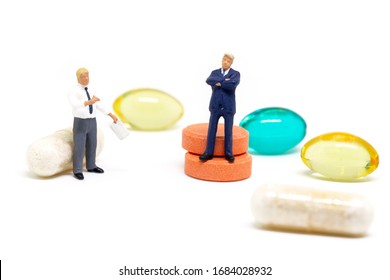 Businessman And Scientist On Medical Pills Background. Miniature Figurines Conceptual Photo. Pharmacological Industry Research Financing. Pharma Corporation Concept. Medical Drug Production And Profit