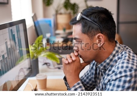 A businessman scrutinises a bar graph at his desk in the office