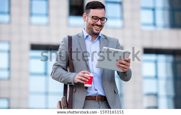 Businessman searching internet with tablet and\
enjoying in coffee break on the way to the office. Business,\
lifestyle concept