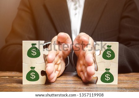 Businessman separates the wooden puzzle with a picture of money. The concept of financial management and distribution of funds. Saving and investing. Property division. Divorce and legal services