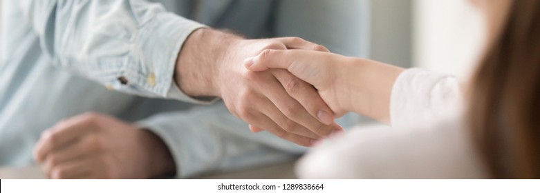 Businessman shaking hands with businesswoman, client and agent greeting gesture. Two people handshaking expressing respect and trust concept. Horizontal close up photo banner for website header design