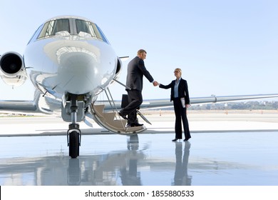 Businessman shaking hands with a businesswoman while getting out of the private jet. - Powered by Shutterstock