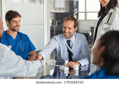 Businessman shaking hands with doctor in meeting room. Doctor and representative pharmaceutical shaking hands in medical office. Salesman with new medicines shaking hands in hospital with medical team