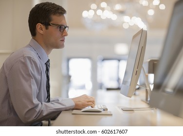 A Businessman In Shirt And Tie Seated At A Computer In A Business Centre Or Office