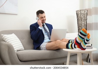 Businessman in shirt, underwear and funny socks talking on phone during video call at home