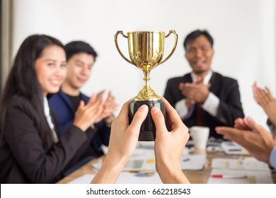 Businessman show thumbs up with trophy, reward, winner, champion and successful for business