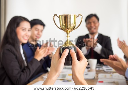 Businessman show thumbs up with trophy, reward, winner, champion and successful for business