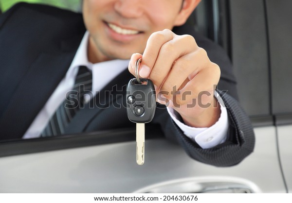 Businessman showing a car key - car sale &\
rental business\
concept