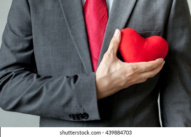 Businessman Showing Compassion Holding Red Heart Onto His Chest In Suit - Crm, Service Mind Business Concept