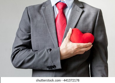 Businessman Showing Compassion Holding Red Heart Onto His Chest In Suit - Crm, Service Mind Business Concept