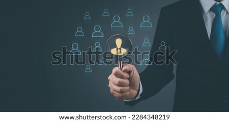 Businessman showing human resources virtual icon or HRM, magnifying glass focus on manager icon, one of employee icons for leadership service, leading organization in recruiting and prospecting.