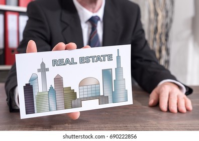 Businessman Showing An Index Card With Real Estate Concept