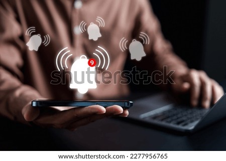 Businessman showing Notification bell button via smartphone app alerts bell ringing for application notification alert concept.