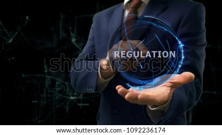 Businessman shows concept hologram Regulation on his hand. Man in business suit with future technology screen and modern cosmic background