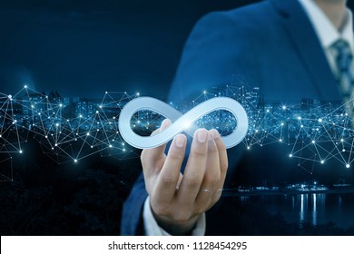 Businessman shows sign of infinity on the background of the city. The concept of unlimited Internet.