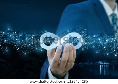 Businessman shows sign of infinity on the background of the city. The concept of unlimited Internet.