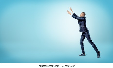 A businessman in side view with both hands raised up trying to catch something above. Loss of fortune. Grab your luck. Catching fortune. - Powered by Shutterstock