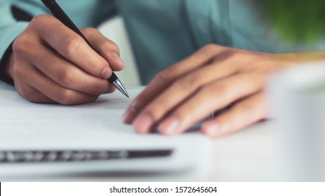 Businessman signing a document after reading the agreement in office - Shutterstock ID 1572645604
