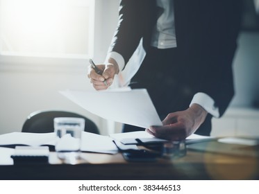 Geschäftsmann, der Dokumente an einem Schreibtisch mit schwarzem und weißem Hemd unterzeichnet, Nahaufnahme von Händen, gefiltriertes Bild, flare Licht