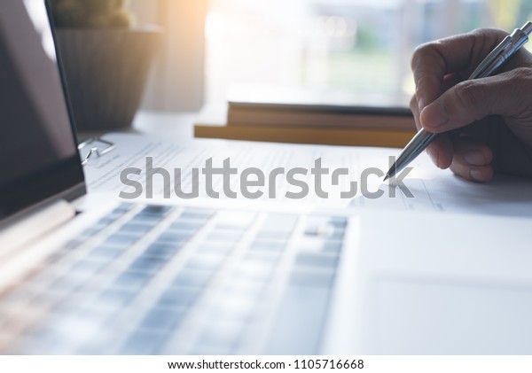 Businessman\
signing official contract with laptop computer on office desk.\
business agreement, deal concept. close\
up