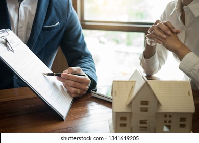 Businessman signs contract behind home architectural model
Discussion with a real estate agent rental company staff 
at the office property appraisal and valuation concept - Powered by Shutterstock