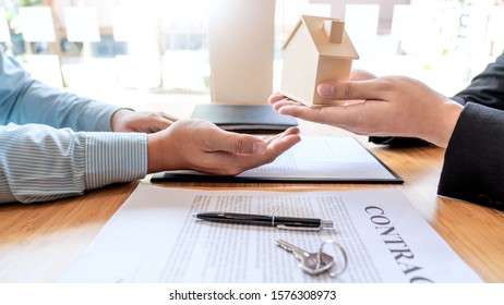 Businessman signs contract behind home architectural model Discussion with a real estate agent rental company staff  at the office property appraisal and valuation concept - Powered by Shutterstock