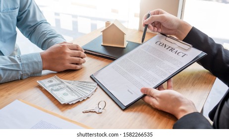 Businessman signs contract behind home architectural model Discussion with a real estate agent rental company staff  at the office property appraisal and valuation concept