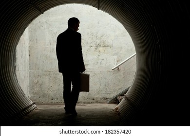 Businessman In Silhouette Walking In A Dark Tunnel. With Room For Your Text