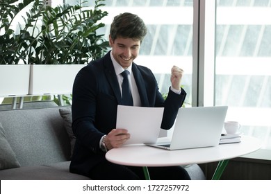 Businessman sit at desk read paper financial documents feels excited by sales increase, celebrate profitable deal, receive lucrative contract, good project results, entrepreneur get bank loan approval