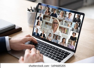 Businessman sit at desk use computer working on-line communicate distantly with colleagues by videoconferencing diverse people engaged in group video call, advertise worldwide virtual chat app concept