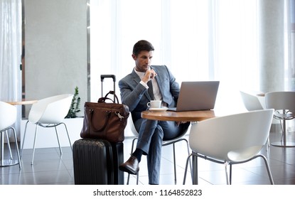 Businessman Sitting In Airport Business Lounge And Looking At Laptop On Table. Business Man Sitting At Airport Lounge With Laptop.