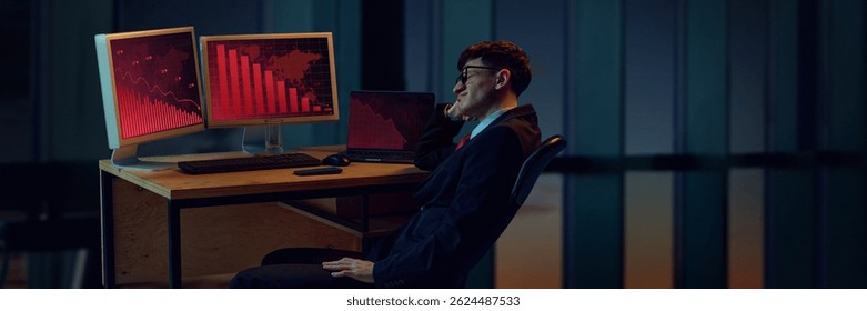 Businessman sitting back in office, looking at two computer screens displaying red graphs indicating significant downward trend. Market crash. Business, crisis, failure, leadership, downturn concept