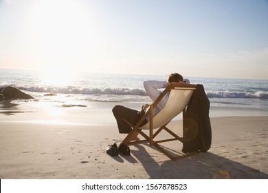 Businessman sitting in deck chair at beach