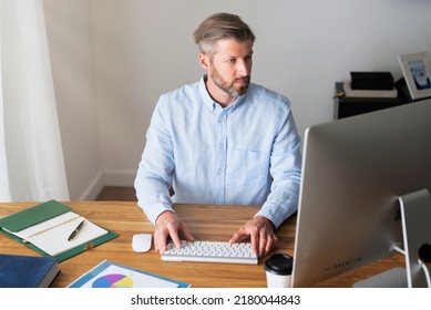 Businessman Sitting At Desk Behind His Computer While Working From Home. Home Office. 