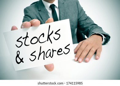 businessman sitting in a desk showing a signboard with the text stocks and shares written in it
