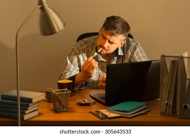 Businessman Sitting At The Desk And Smoking Cigarette