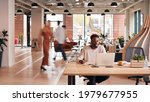 Businessman Sitting At Desk Writing In Notebook In Modern Open Plan Office