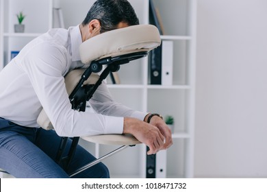 Businessman Sitting In Massage Chair At Office