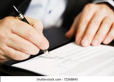 Businessman Sitting At Office Desk Signing A Contract With Shallow Focus On Signature.