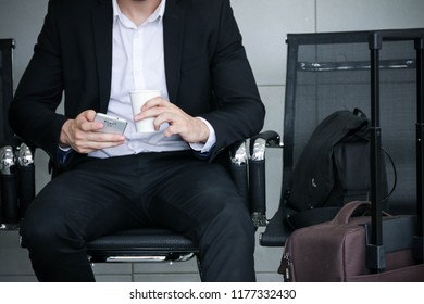 a businessman sitting on chair while waiting in airport room with using smart phone communication