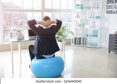 Businessman Sitting On Fitness Ball While Working In Office