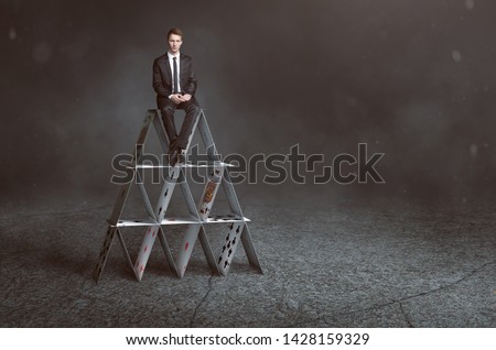 Businessman is sitting on house of cards 