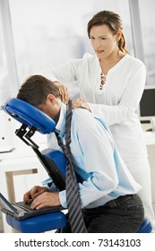 Businessman sitting on massage chair, getting back massage.?