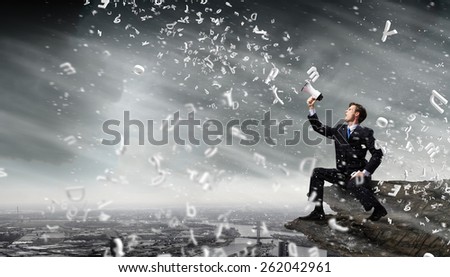 Businessman sitting on rock edge and screaming in megaphone
